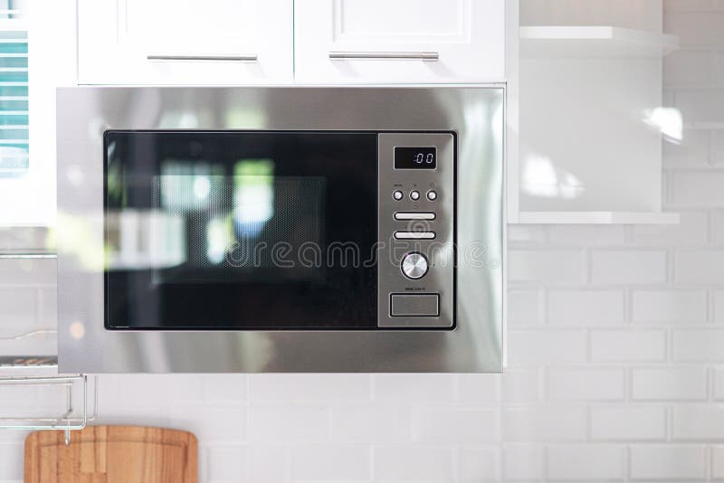 Microwave oven float and hanging under the cabinet on the wall in the kitchen. Interior design of cooking area for compact space