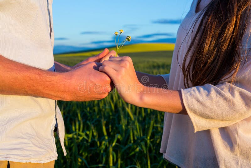 Mid section of couple holding hands in field on a sunny day