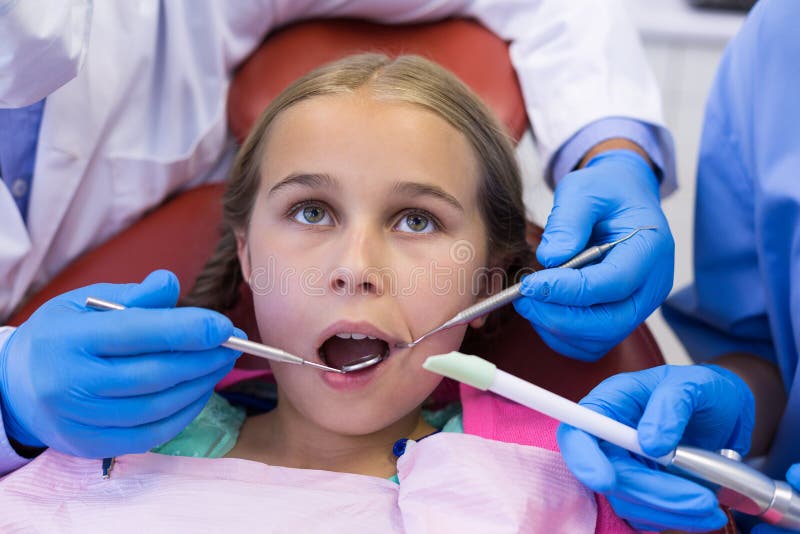 Mid Section of Dentist and Nurse Examining a Young Patient with Tools
