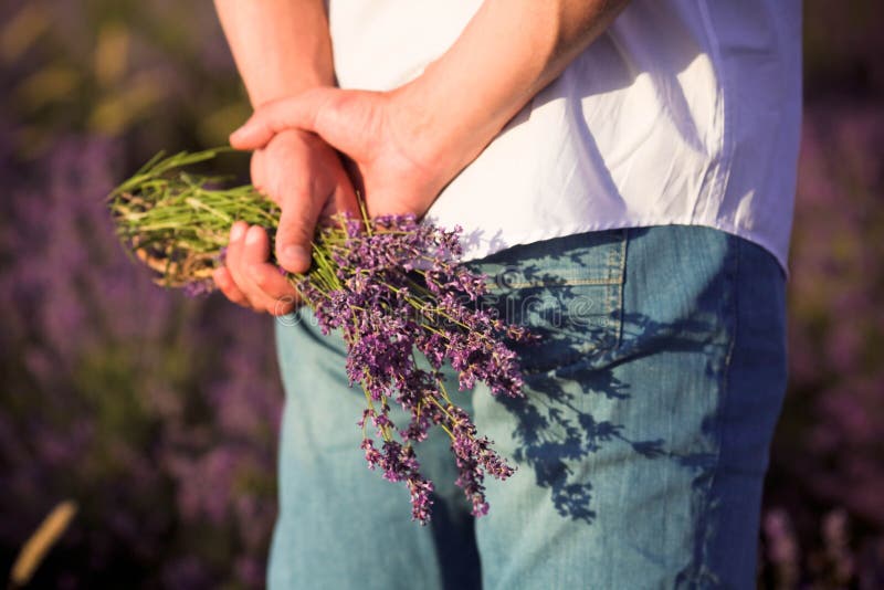 Mid-section of man hiding lavender bouquet behind back