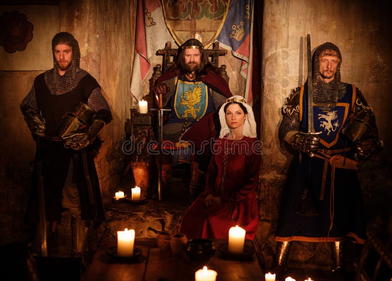 Middeleeuwse koning met zijn koningin en ridders op wacht in oud kasteelbinnenland