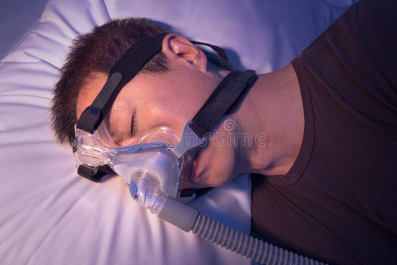 Middle Age Asian Man With Sleep Apnea Sleeping Using CPAP Machin