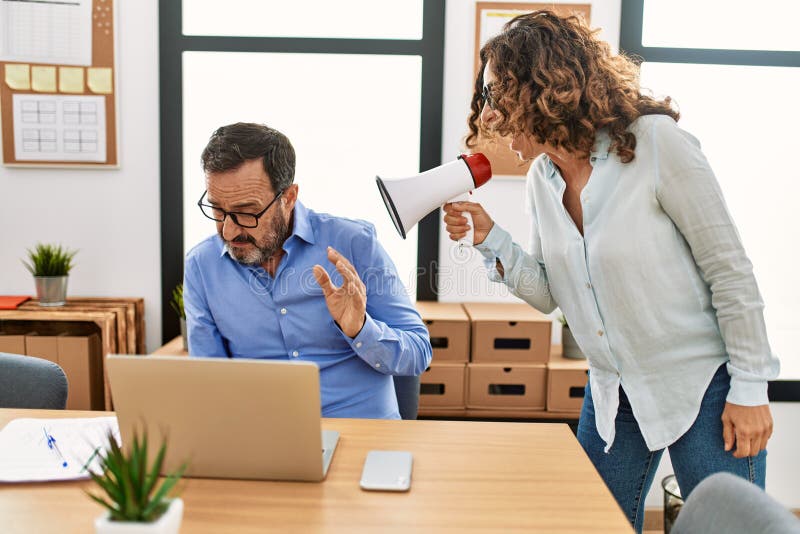 Middle age businesswoman angry with employee. Screaming using megaphone at the office