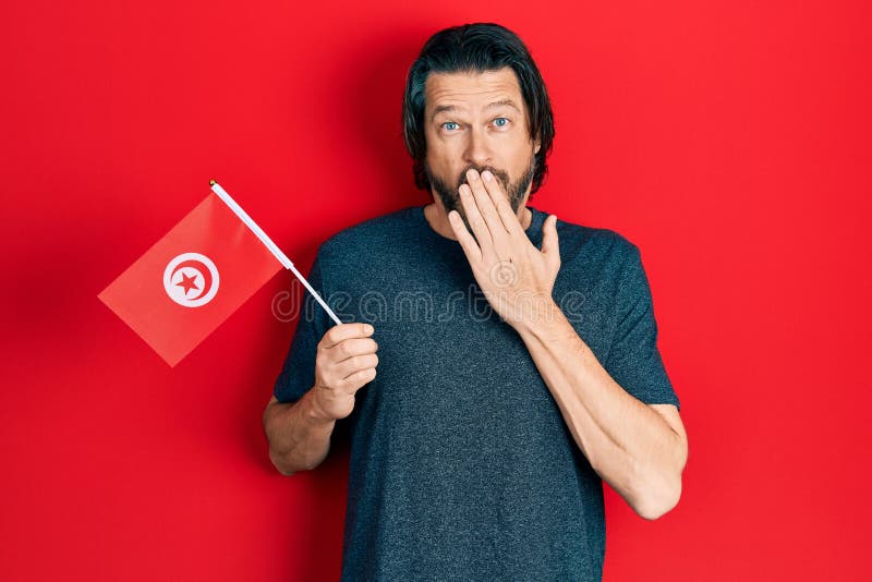 Middle Age Caucasian Man Holding Tunisia Flag Covering Mouth With Hand Shocked And Afraid For 