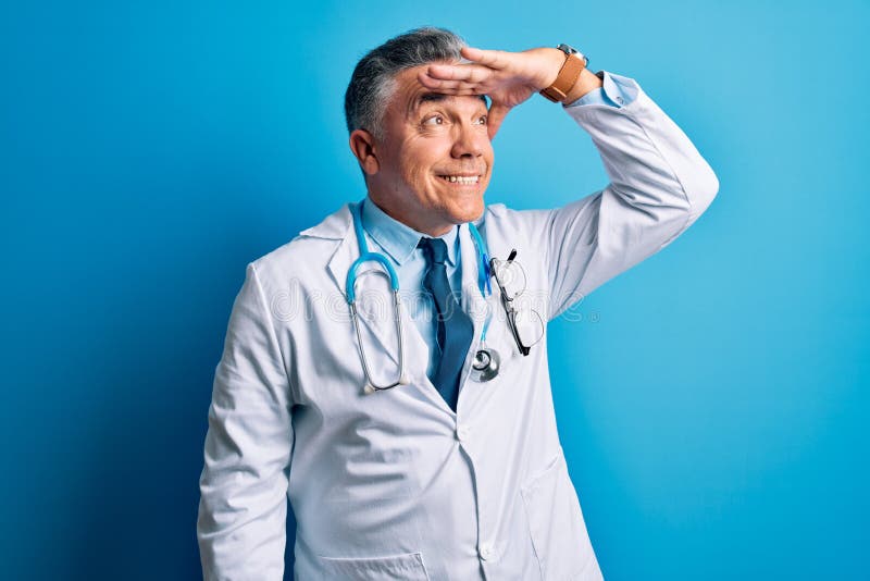 Middle age handsome grey-haired doctor man wearing coat and blue stethoscope very happy and smiling looking far away with hand