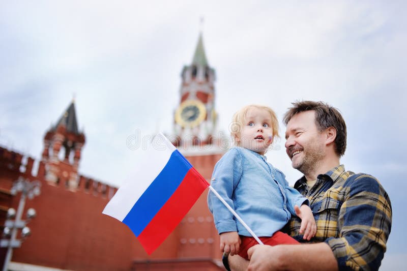 Middle age man and his little son with russian flag with Spasskaya tower Russia, Moscow on background