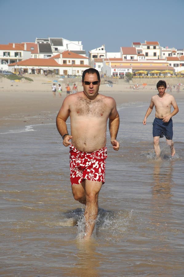 Middle age man running full of energy on the beach