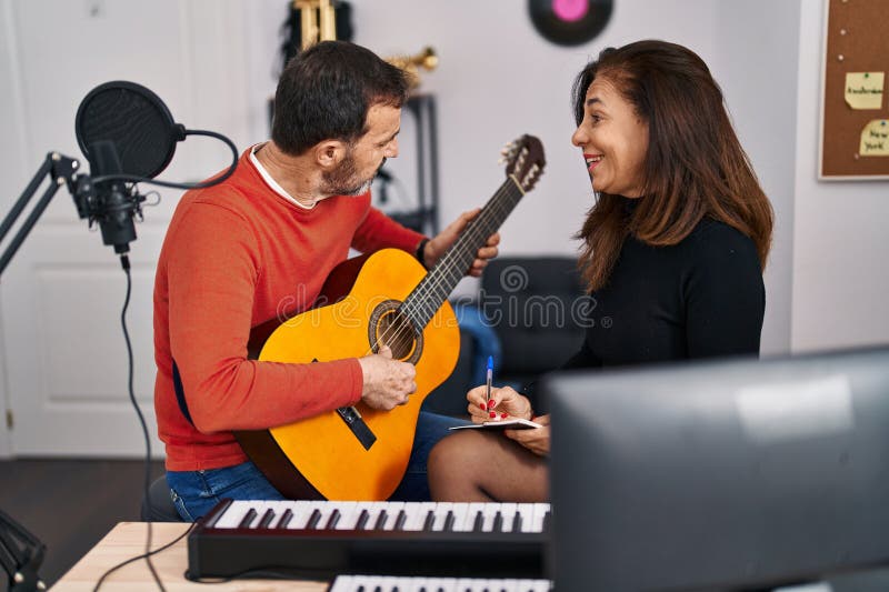 Middle age man and woman musicians having guitar class at music studio stock images