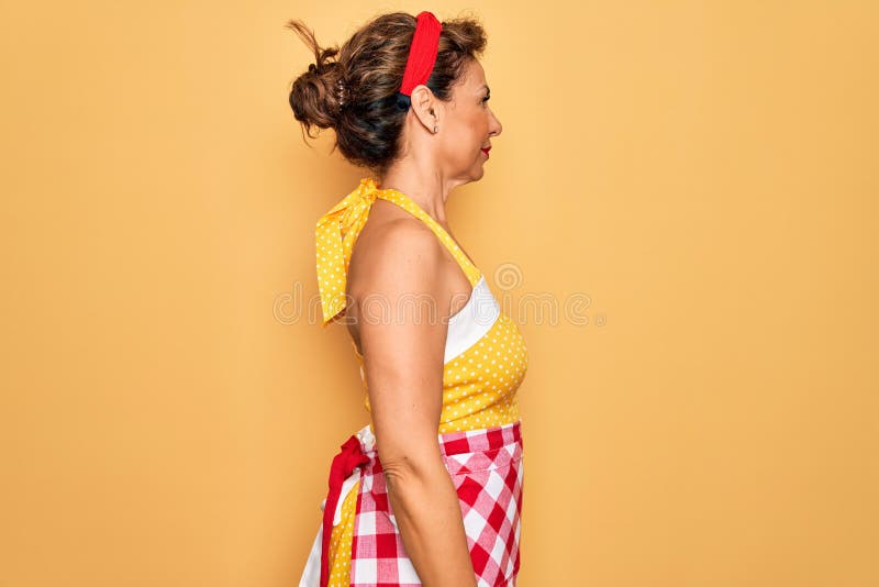 Middle Age Senior Pin Up Housewife Woman Wearing 50s Style Retro Dress And Apron Looking To Side