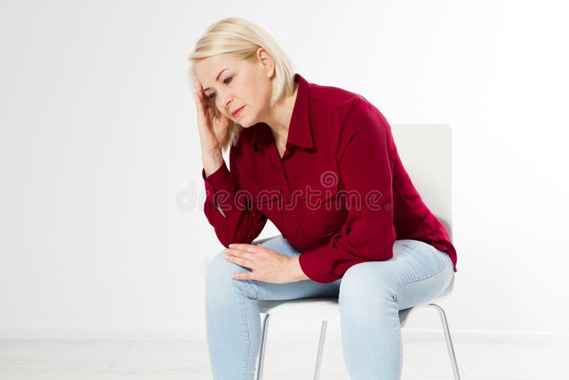 Middle age woman head pain migraine, Beautiful sad middle-aged woman sits on a chair, she has a headache