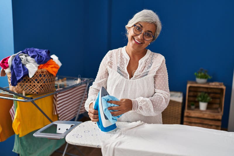 Middle Age Woman Smiling Confident Cleaning Iron at Laundry Room Stock