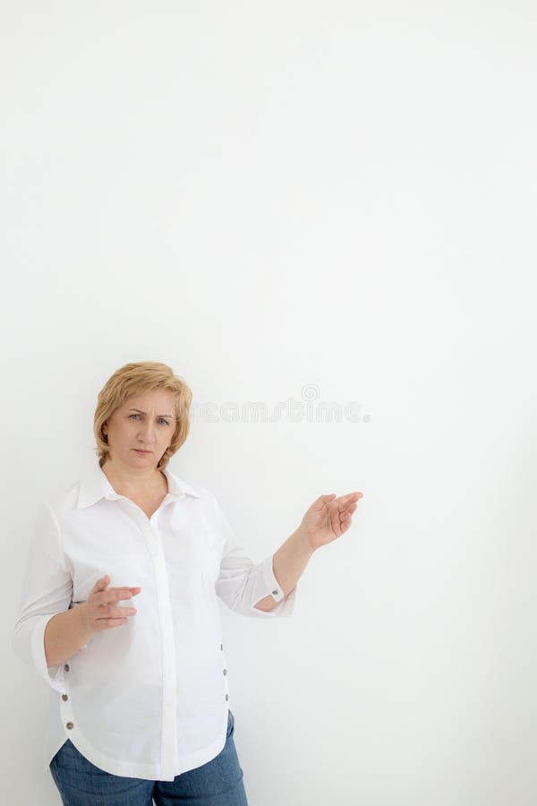 middle aged business woman points with hands to space for text on white background. Old senior businesswoman