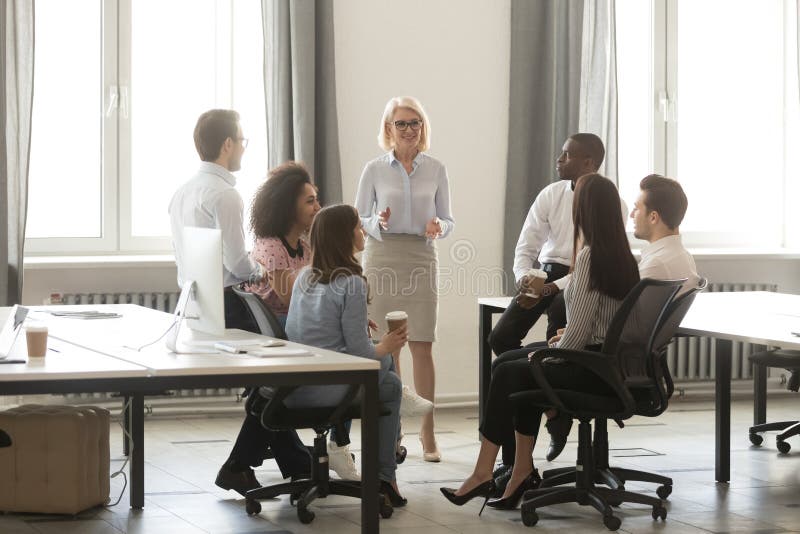 Middle aged businesswoman boss mentor training interns employees in office