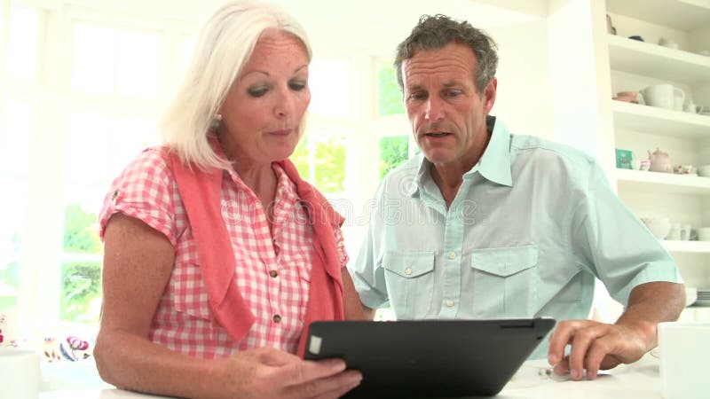 Middle Aged Couple Looking At Digital Tablet Having Argument