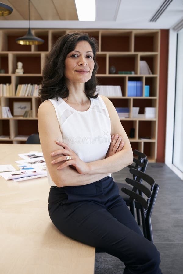 Middle aged female creative sitting on the desk in an office royalty free stock photo Middle aged female creative sitting on the desk in an office royalty free stock photo