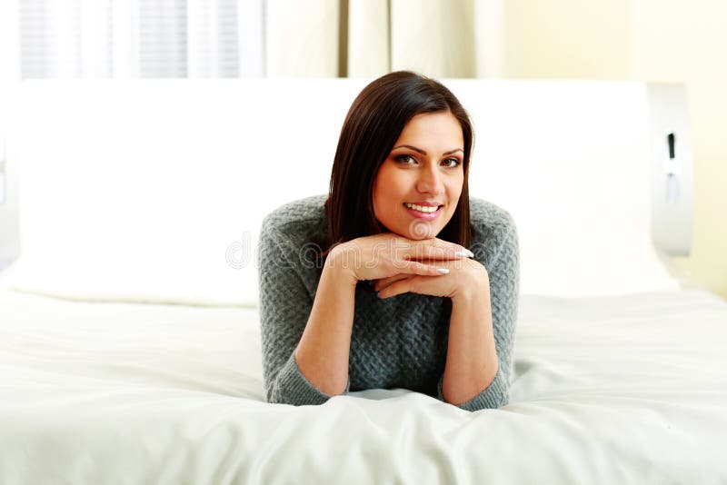 Middle-aged happy smiling woman lying on the bed stock photography Middle-aged happy smiling woman lying on the bed stock photography