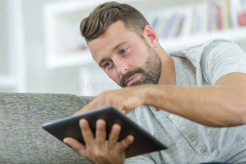 Middle-aged man using digital tablet on sofa royalty free stock image