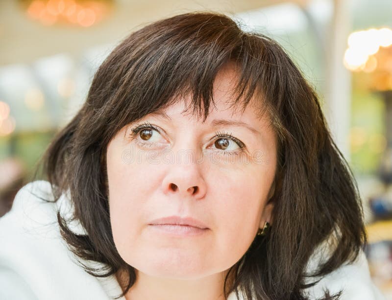 Middle-aged woman brown eyes is sitting in the apartment stock photo Middle-aged woman brown eyes is sitting in the apartment stock photo