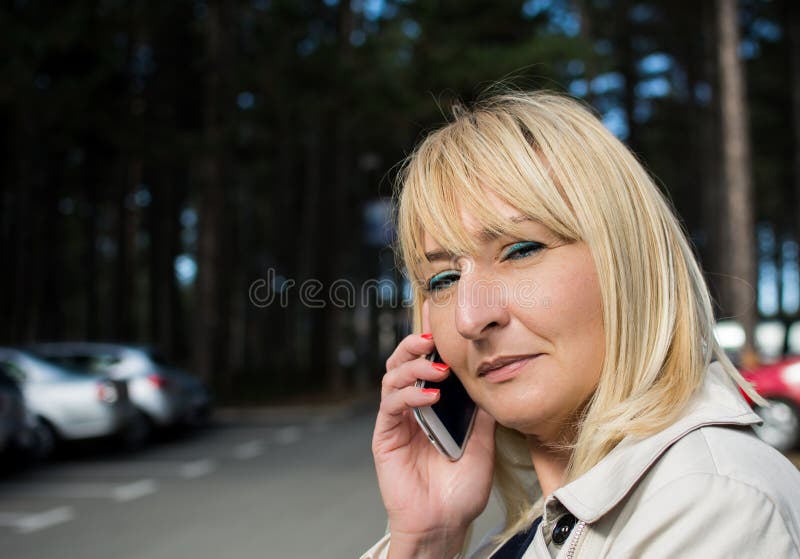 Middle aged woman talking on mobile. Blond hair. Smiling. stock photography Middle aged woman talking on mobile. Blond hair. Smiling. stock photography