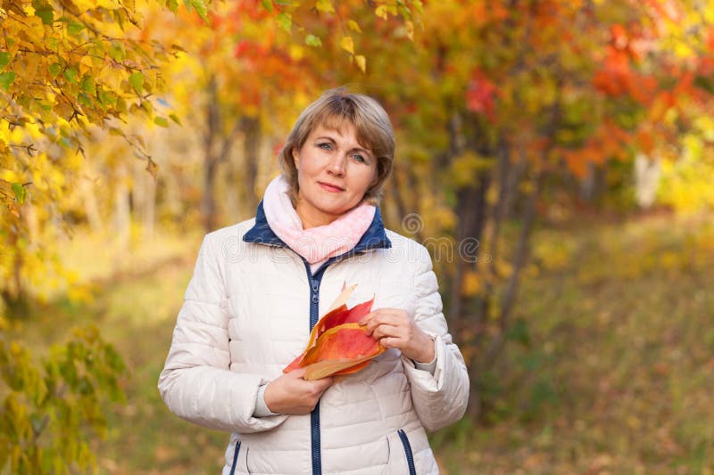 A middle-aged woman walks in the autumn Park among the trees