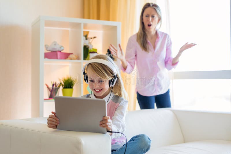 Woman is scolding her teenage daughter, girl is listening to music in headphones and ignoring her mom royalty free stock photography Woman is scolding her teenage daughter, girl is listening to music in headphones and ignoring her mom royalty free stock photography