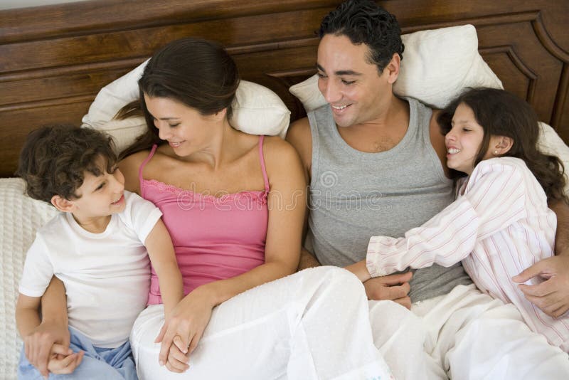 A Middle Eastern family lying on a bed stock photos