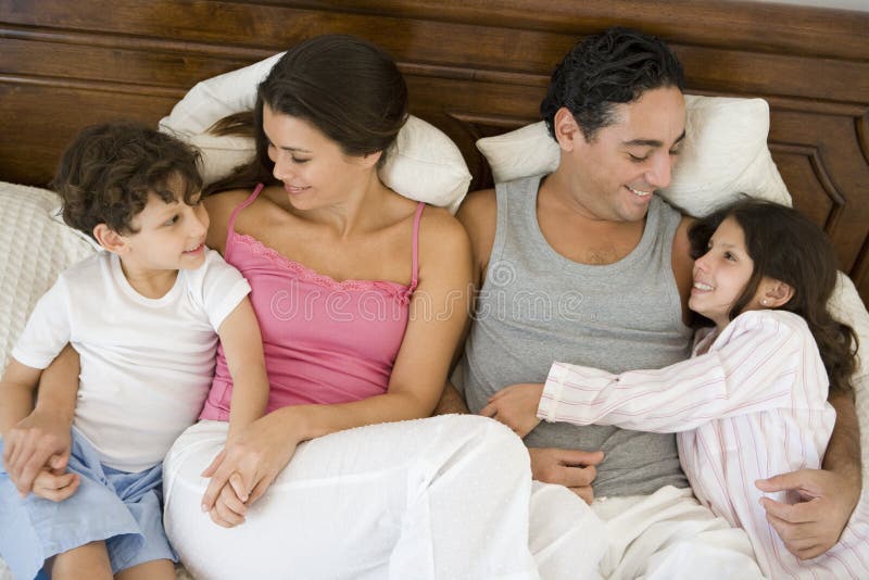 A Middle Eastern family lying on a bed royalty free stock photo