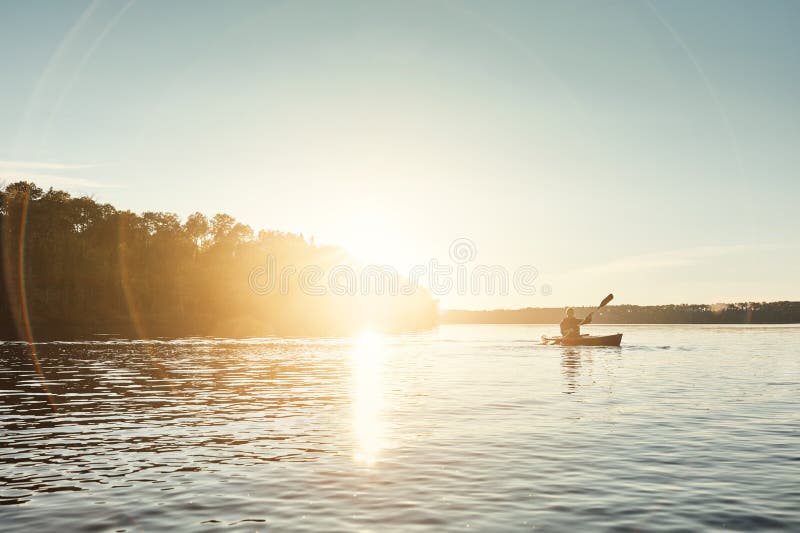 In the middle of nowhere is where you find yourself. a young man kayaking on a lake outdoors. royalty free stock images