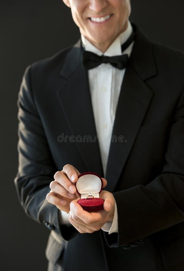 Midsection Of Happy Man In Tuxedo Holding Ring Box