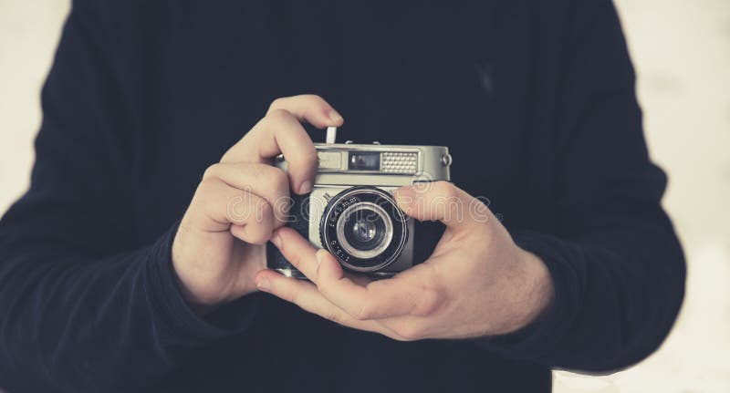 Midsection of a man holding a vintage, 35mm camera