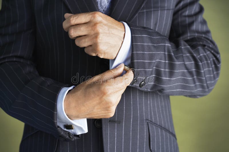 Closeup midsection of a businessman in suit buttoning cuff sleeves. Closeup midsection of a businessman in suit buttoning cuff sleeves