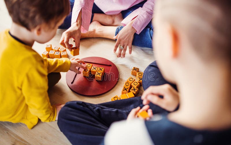 Midsection van moeder met twee kinderen die raadsspelen op de vloer spelen stock fotografie Midsection van moeder met twee kinderen die raadsspelen op de vloer spelen stock fotografie