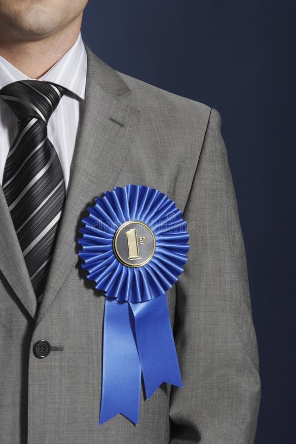 Closeup midsection of a businessman wearing blue ribbon on lapel against dark background mid section. Closeup midsection of a businessman wearing blue ribbon on lapel against dark background mid section