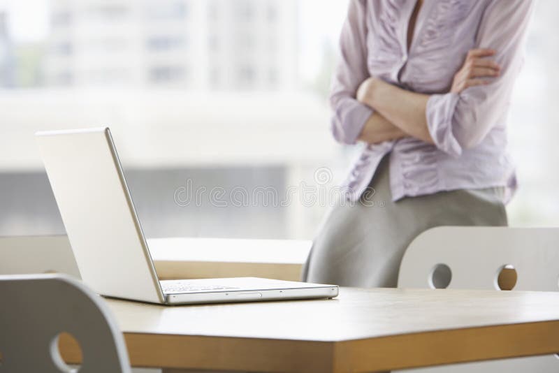 Midsection of a businesswoman with focus on laptop in foreground at office. Midsection of a businesswoman with focus on laptop in foreground at office