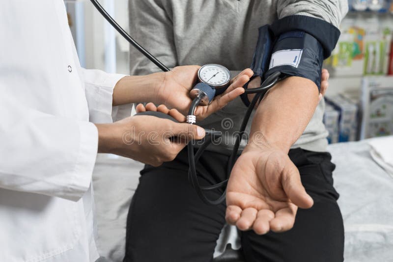 Midsection of nurse checking blood pressure of senior patient in pharmacy. Midsection of nurse checking blood pressure of senior patient in pharmacy