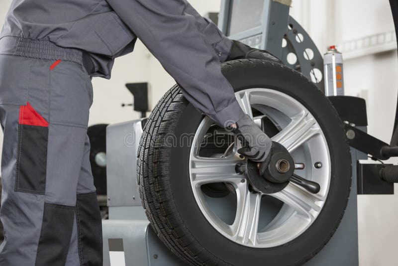 Midsection of male mechanic repairing car's wheel in repair shop. Midsection of male mechanic repairing car's wheel in repair shop