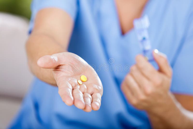 Midsection of male caretaker giving medicine at nursing home. Midsection of male caretaker giving medicine at nursing home