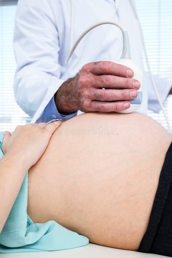 Midsection доктора выполняя ультразвук на женщине стоковое фото