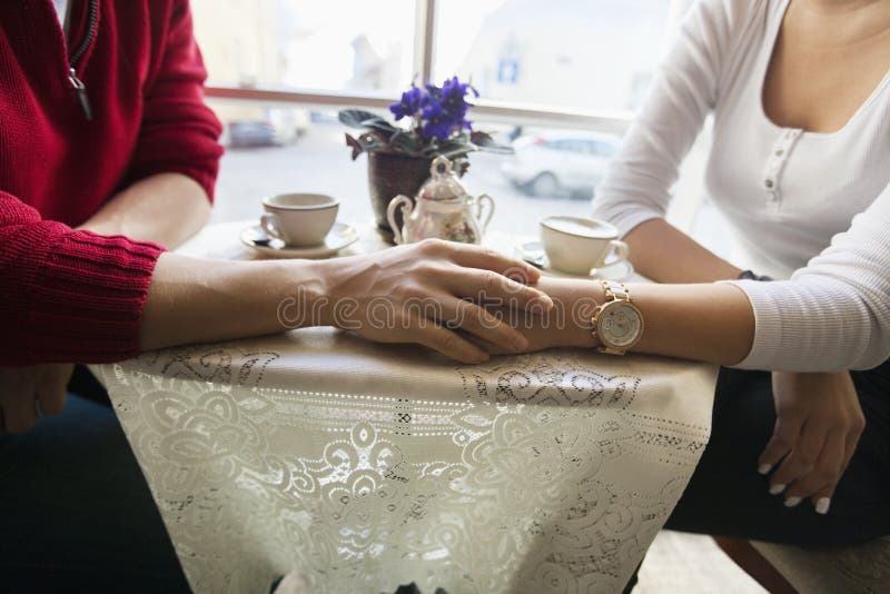 Midsection of couple holding hands in cafe. Midsection of couple holding hands in cafe