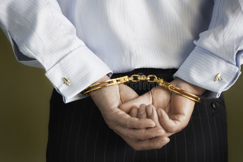 Closeup midsection of a businessman with hands cuffed behind back against green background. Closeup midsection of a businessman with hands cuffed behind back against green background