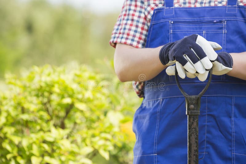 Midsection of gardener holding spade in plant nursery. Midsection of gardener holding spade in plant nursery