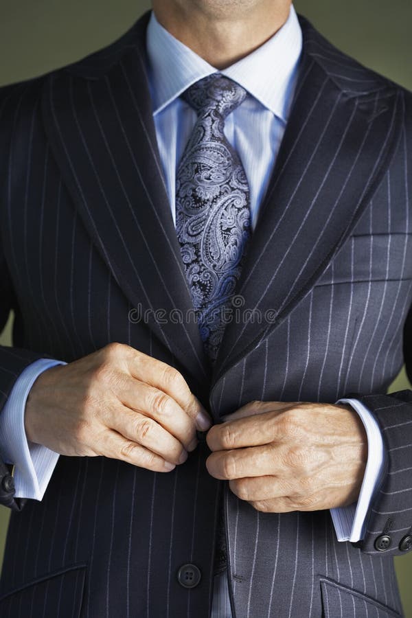 Closeup midsection of a businessman in suit buttoning button on Coat. Closeup midsection of a businessman in suit buttoning button on Coat