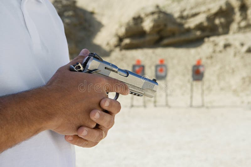 Midsection of a men holding handgun at firing range during training. Midsection of a men holding handgun at firing range during training