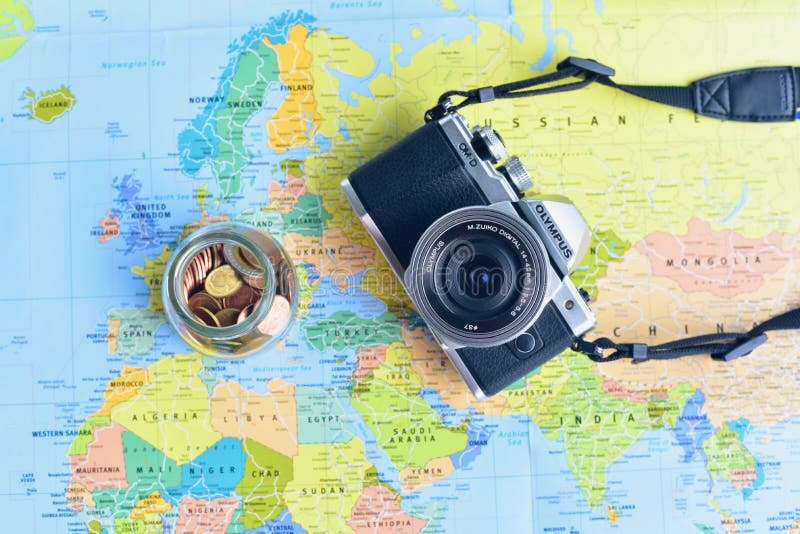 Mieszkanie Lay Mirrorless kamera i Szklany słój Wypełniający z brąz monetami Odizolowywać na Światowej mapy tle zdjęcie royalty free Mieszkanie Lay Mirrorless kamera i Szklany słój Wypełniający z brąz monetami Odizolowywać na Światowej mapy tle zdjęcie royalty free