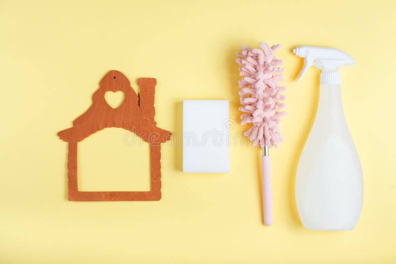 Flat lay, cleaning tools on yellow background, melamine sponge and duster, spray, wooden frame house with copy space, top view. Flat lay, cleaning tools on yellow background, melamine sponge and duster, spray, wooden frame house with copy space, top view