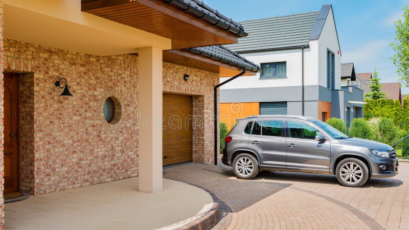 Mieszkaniowy dom z srebnym suv samochodem parkującym na podjeździe w fron