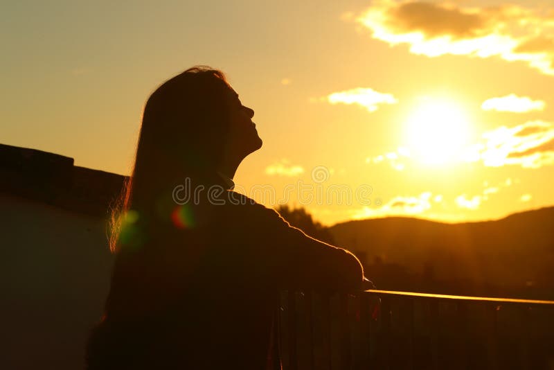 Backlight tenant silhouette breathing fresh air in a balcony at sunset. Backlight tenant silhouette breathing fresh air in a balcony at sunset