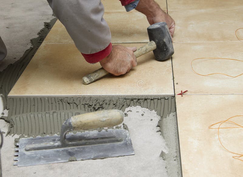 Miglioramento domestico, rinnovamento - il piastrellista del muratore sta piastrellando, adesivo del pavimento della piastrella d immagini stock Miglioramento domestico, rinnovamento - il piastrellista del muratore sta piastrellando, adesivo del pavimento della piastrella d immagini stock