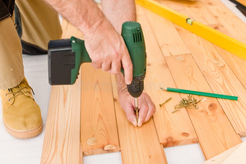 Miglioramento domestico - uomo che installa pavimento di legno fotografia stock Miglioramento domestico - uomo che installa pavimento di legno fotografia stock