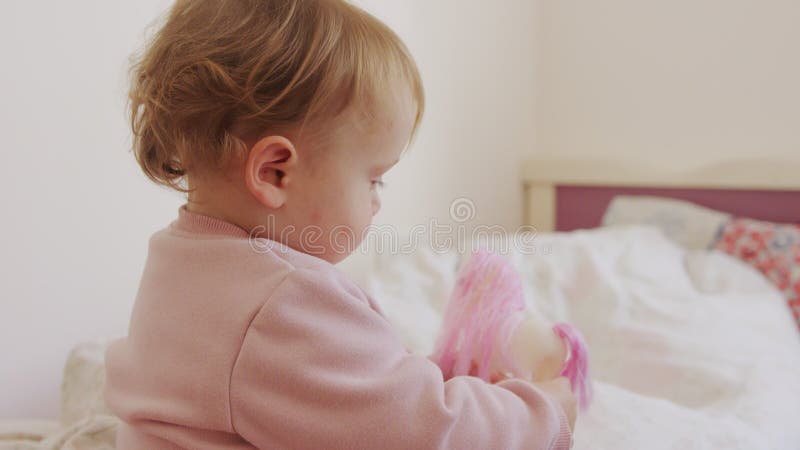 Mignon bébé assis sur un lit qui joue du roulement et rire banque de vidéos